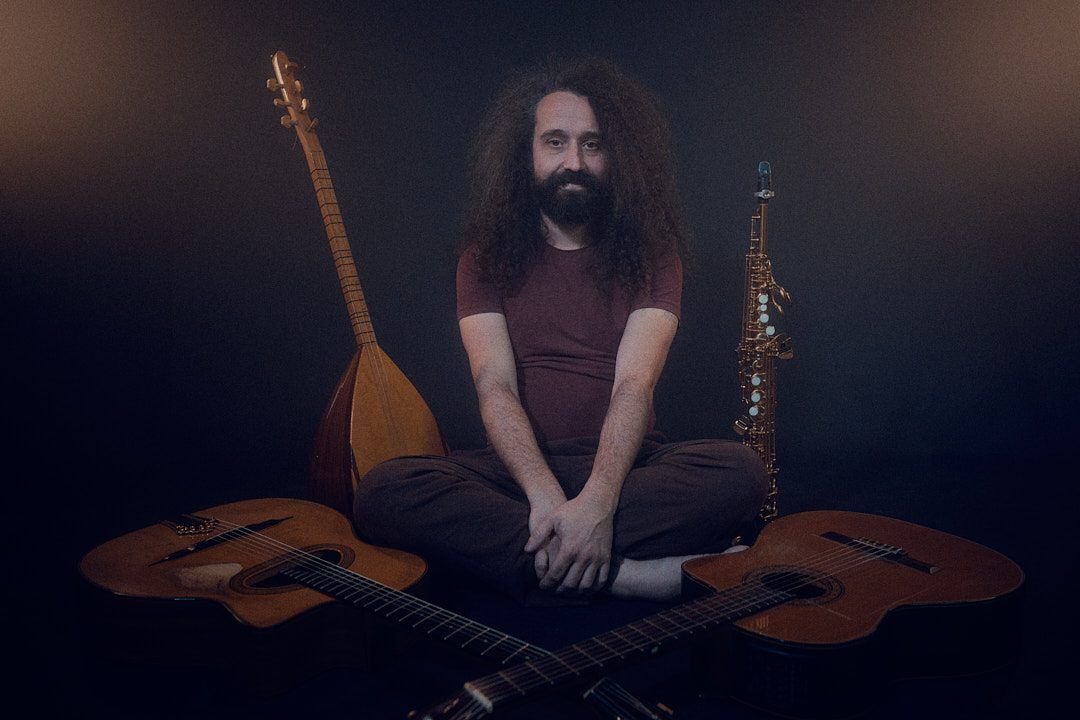 Giulio Gavardi seated among guitars and other string instruments